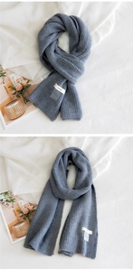 Détail d'une écharpe en maille côtelée bleu gris avec étiquette HORN et texture de laine