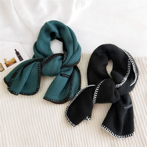 Knitted winter scarves in dark green and black with contrast stitching and woven labels
