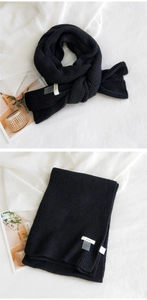 Détail d'une écharpe en maille noire avec étiquette HORN et texture côtelée