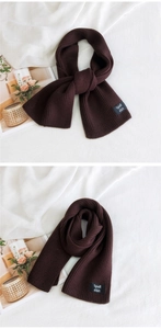 Detail of solid coffee brown ribbed knit scarf with fashion label on white fabric