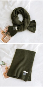 Détail de la texture en maille verticale et de l'étiquette de marque tissée de l'écharpe vert olive
