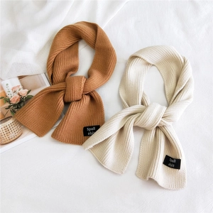 Caramel and off-white knitted scarves with fashion patch labels on soft textured background