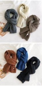 Close-up of thick knitted winter scarves in six colors including grey, beige, and blue
