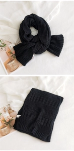 Close-up of thick black chunky knit scarf with ribbed texture and warm woven detail