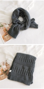 Detailed macro view of dark grey chunky knit scarf with vertical stripes and label