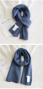 Detail of navy blue ribbed knit scarf showing soft thick wool texture and logo label