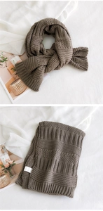 Detail of thick dark coffee chunky knit scarf texture with a white woven label