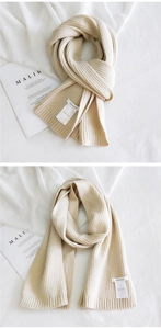 Detailed knit texture and logo patch of a thick beige winter scarf in cozy styling