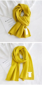 Detail view of the thick ginger yellow ribbed knit scarf with a white brand label