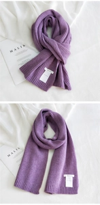 Macro detail of dark purple chunky knit scarf with vertical ribbing and white label tag