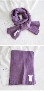 Detailed texture of purple knitted scarf with ribbed pattern and brand woven label