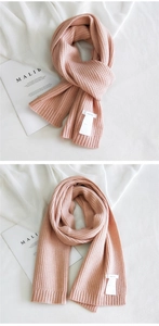 Close-up of pink chunky knit scarf with vertical rib pattern and woven label detail