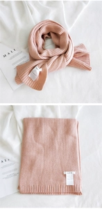 Detailed view of pink knitted scarf with vertical stripe texture and brand label