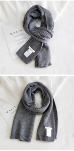 Close-up of grey ribbed knit scarf showing texture and sewn fabric brand label