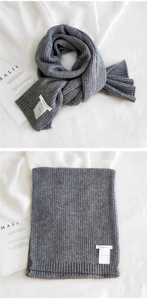 Close-up of gray chunky knit scarf featuring ribbed texture and white woven label