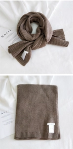 Detail of dark brown knitted scarf with vertical rib texture and white brand label
