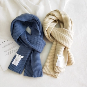 Thick ribbed knit scarves in navy blue and beige with woven brand label on white fabric
