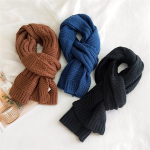 Thick knitted scarves in brown, navy and black displayed on minimalist white fabric