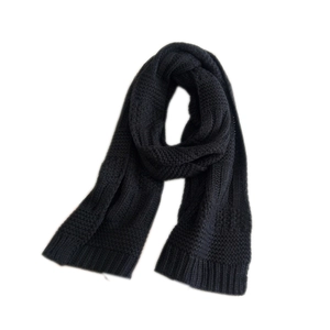 Thick black knitted scarf with honeycomb texture and ribbed edges on white background