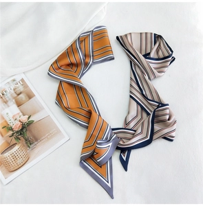 Détail d'un foulard twilly en satin rayé double face aux tons élégants orange et beige