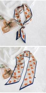 Détail d'un foulard gris en soie avec motif floral orange et bordure bleu marine