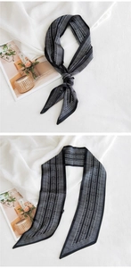 Gros plan d'un foulard étroit en soie noir et blanc avec motif géométrique noué