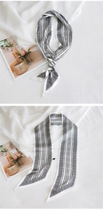 Détail d'un foulard étroit en soie à motif géométrique noir et blanc sur fond blanc