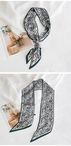 Détail d'un foulard étroit en soie zébré vert et blanc sur fond de magazine élégant