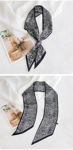 Détail d'un foulard long en soie avec imprimé léopard noir et blanc et bordure passepoilée
