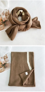 Detailed view of striped brown knit scarf texture and premium woven brand label
