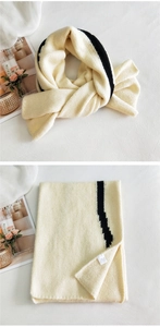 Detail of soft cream knitted scarf featuring a contrasting black stripe and thick texture