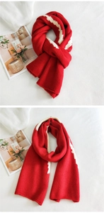 Detail of red knit scarf with white wavy stripes showing thick soft texture and stitching