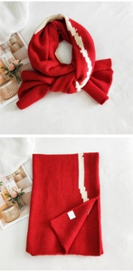 Detail of red thick knit scarf featuring white contrast stripe pattern and logo tag