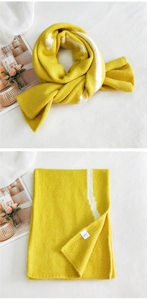 Close-up of thick knitted yellow scarf featuring white stripe detail and soft wool texture
