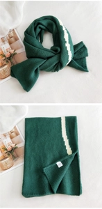 Detail of dark green knitted scarf with white zigzag stripes and soft wool texture