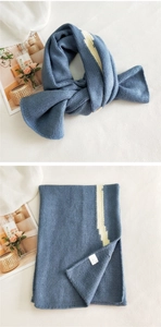 Detail view of thick navy blue knit scarf with white stripes and soft wool texture