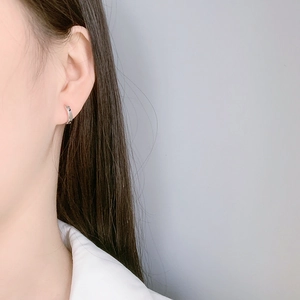 Close-up of minimalist silver hoop earrings on a model showing the polished metallic finish