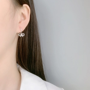 Close-up of a silver bow earring hoop on a model with a clean minimalist style