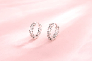 Detail of hollow heart pattern on silver S925 sterling silver hoop earrings with satin