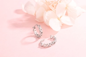 Macro detail of S925 sterling silver hoop earrings with hollow heart pattern engraving