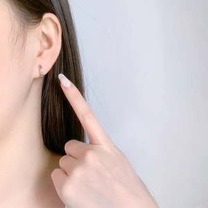 Detail view of small S925 sterling silver hoop earrings with hollow heart design on earlobe