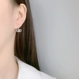 Elegant hollow bow pendant earrings in silver finish worn by a model for daily wear