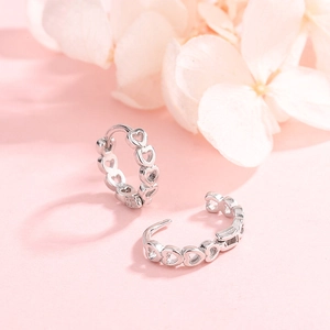 Elegant S925 sterling silver hoop earrings featuring hollow heart patterns on pink floral background