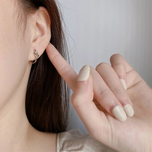 Detail of silver knot stud earrings worn by a model with a minimalist chic aesthetic