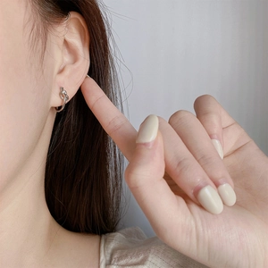 Minimalist silver knot hoop earrings worn on ear with trendy geometric design