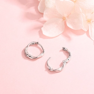 Boucles d'oreilles créoles torsadées en argent sterling S925 sur fond floral rose délicat