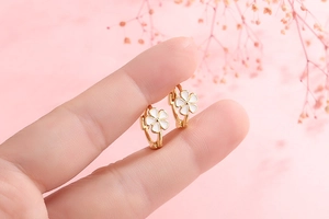 Detail of small s925 silver flower earrings with white enamel finish and gold plating