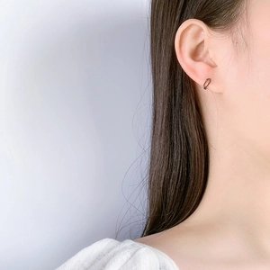 Close-up of a dark grey S925 sterling silver paperclip earring worn by a model