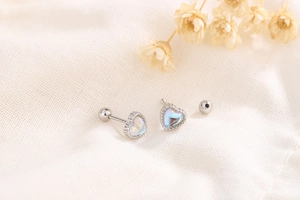 Detail of s925 silver heart stud earrings with moonstone inlay and screw back closure