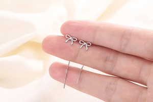 Détail macro de boucles d'oreilles nœud en argent S925 avec chaîne portées à la main